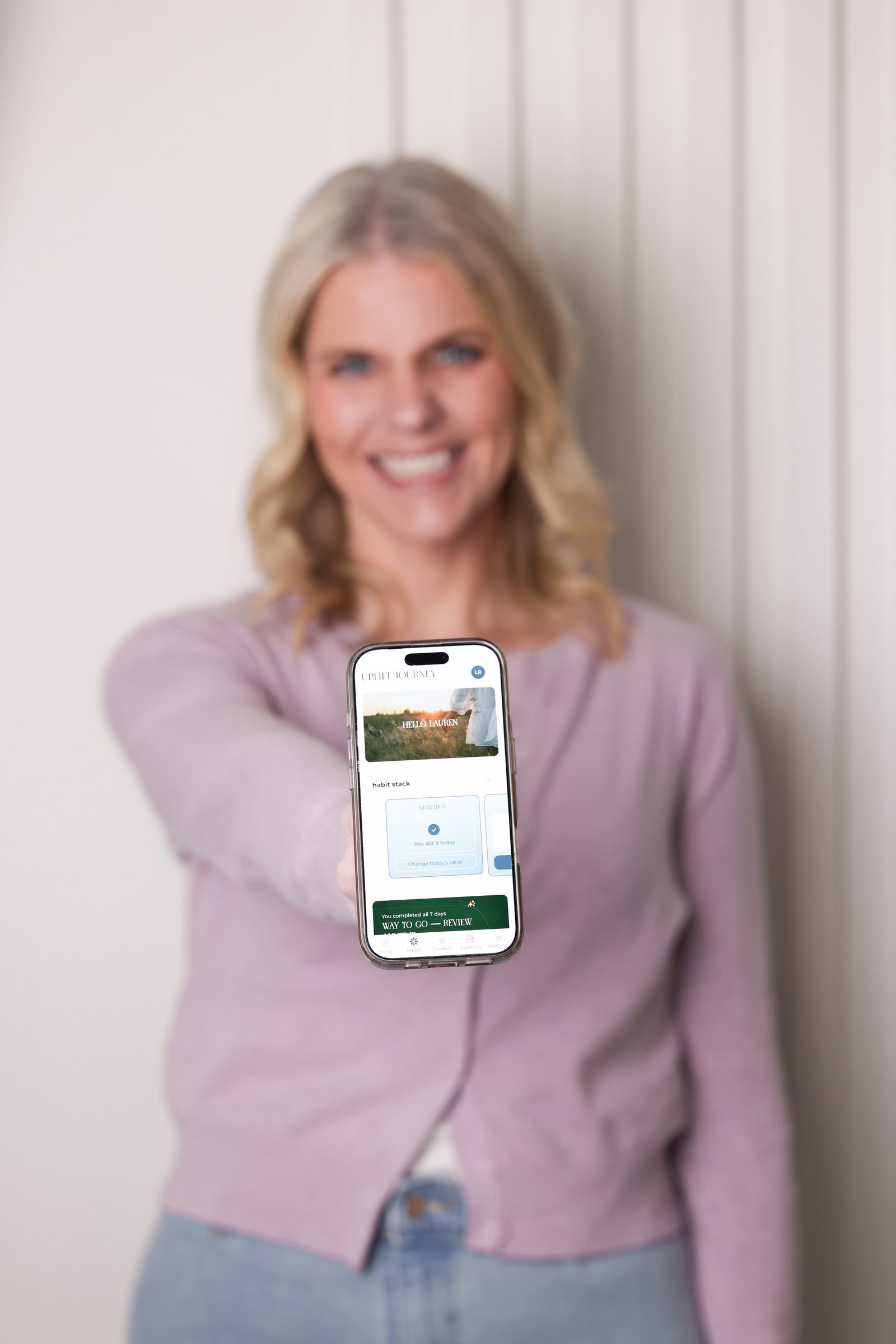 Lauren Rojas holding the Uplift Journey app on her phone